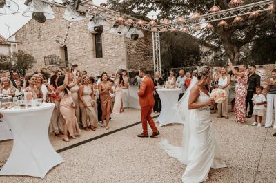 Décor de fête avec ballons beige et blanc, murs en pierre, présentoirs et un ours en peluche au centre.