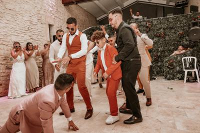 Décor de fête avec ballons beige et blanc, murs en pierre, présentoirs et un ours en peluche au centre.