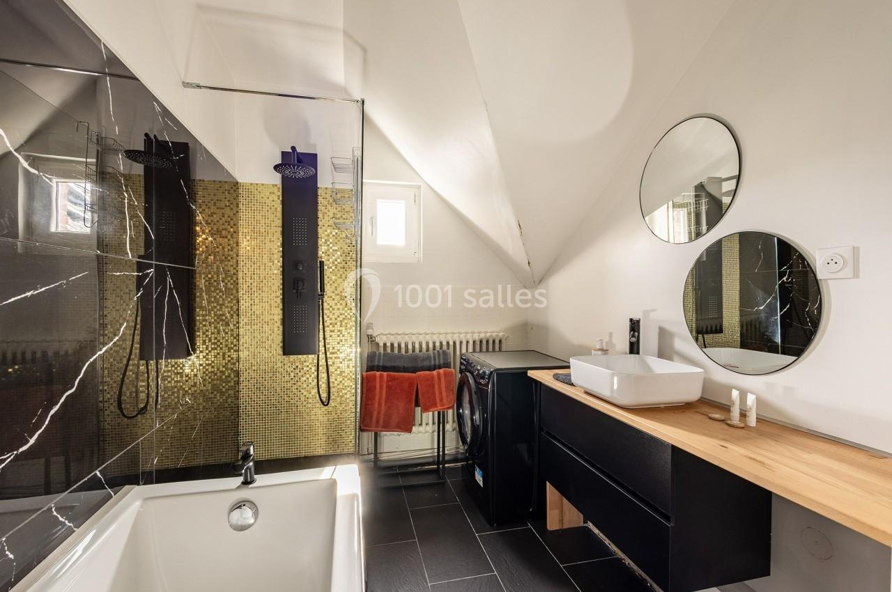 Salle de bain moderne avec baignoire, douche à l'italienne, lavabo sur meuble en bois et murs partiellement carrelés.
