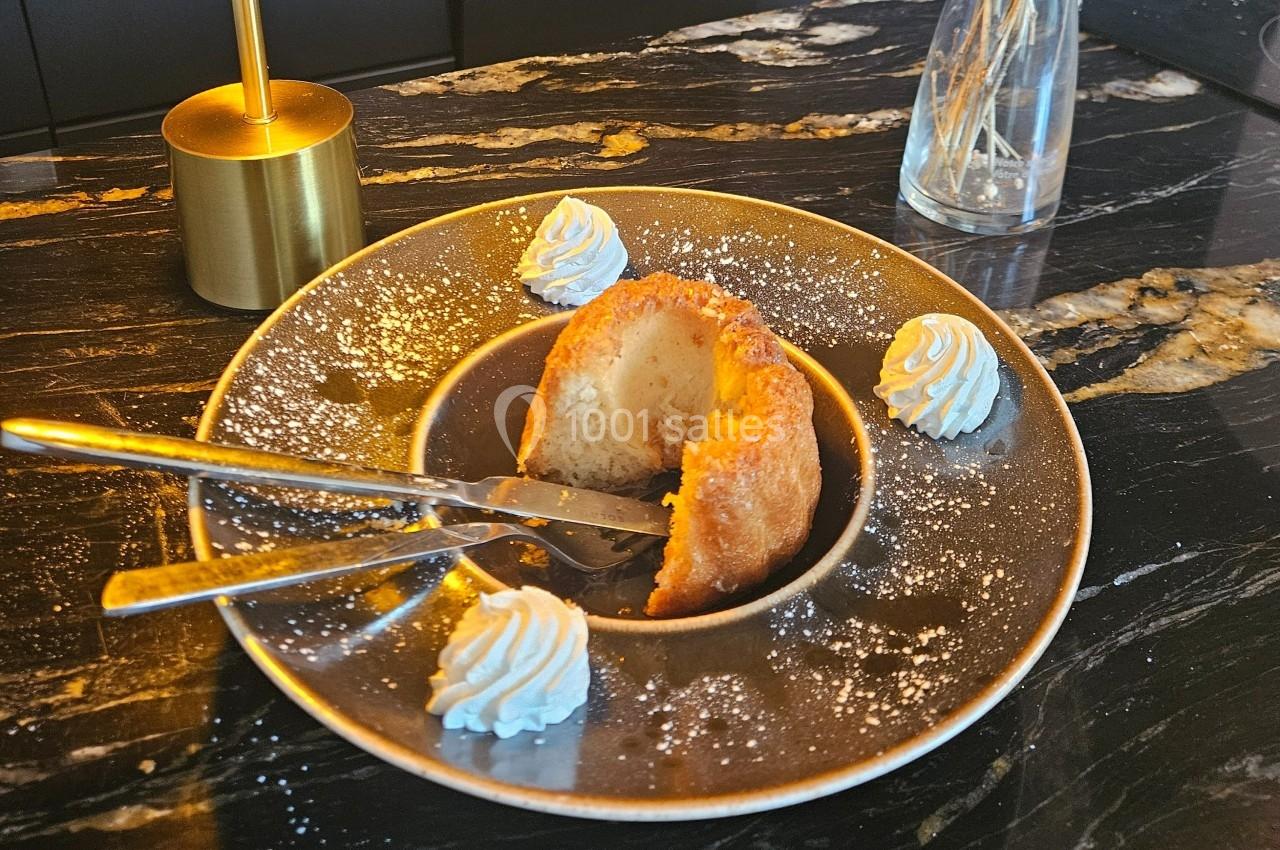 Dessert servi sur une assiette avec un gâteau moelleux, une cuillère, une fourchette et des rosettes de chantilly.