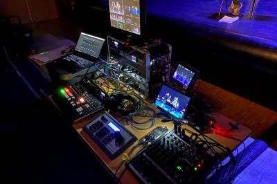 Installation technique avec écrans, projecteurs et équipements audiovisuels dans une salle aux murs clairs.