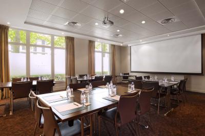 Salle de petit-déjeuner avec buffet varié, tables dressées, éclairage chaleureux et décor moderne en bois sombre.
