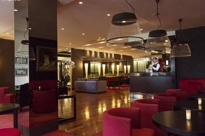 Salle de petit-déjeuner avec buffet varié, tables dressées, éclairage chaleureux et décor moderne en bois sombre.