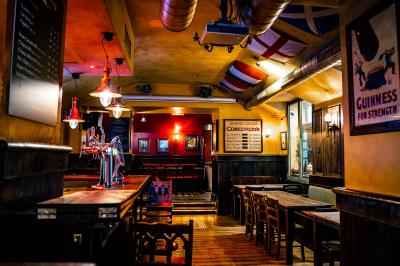 Miniature Location salle Paris 2 (Paris) - Corcoran's Grands Boulevards #7 Façade d'un pub irlandais avec enseignes lumineuses vertes et jaunes, devant un bâtiment en pierre.