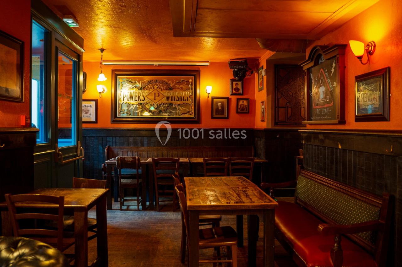 Intérieur d'un café chaleureux avec murs orange, tables en bois, banquettes et éclairage tamisé.