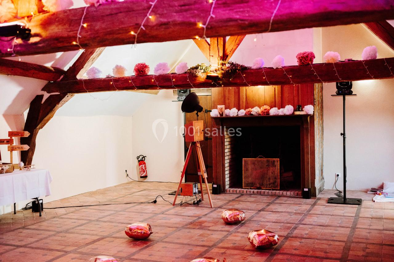 Location salle Wy-dit-Joli-Village (Val-d'Oise) - Château d'Hazeville #12 Salle décorée avec des guirlandes lumineuses et des pompons colorés, avec une cheminée et un appareil photo vintage.