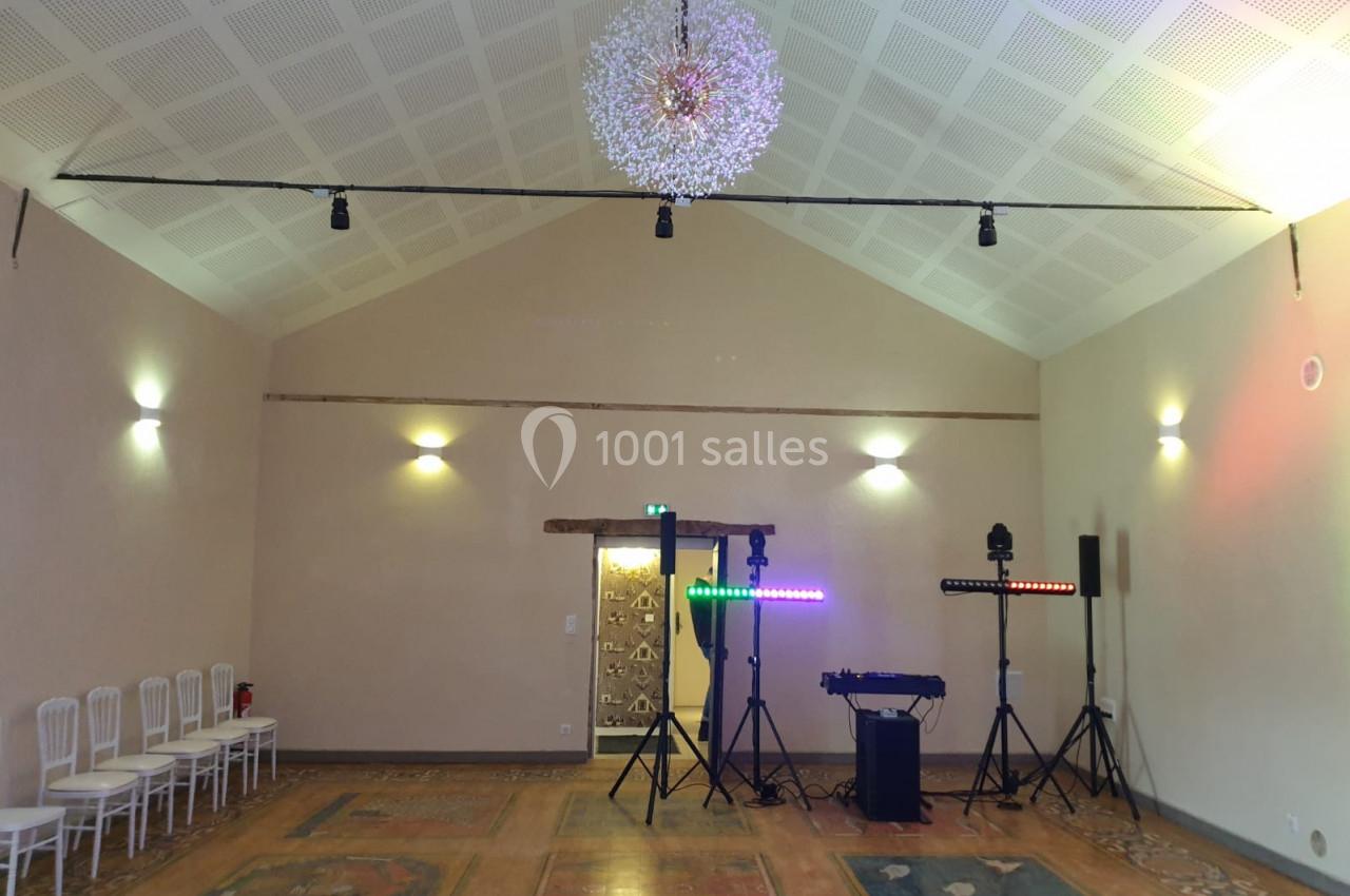 Salle fontaine - 80m² Salle lumineuse avec plafond haut, chaises alignées à gauche, équipements d'éclairage et de son installés au fond.