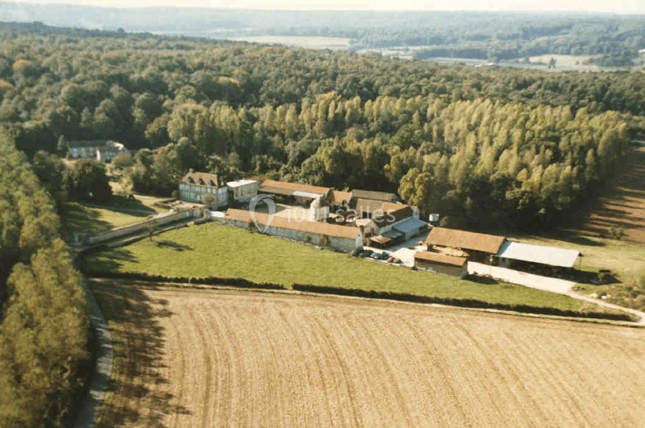 Vue du ciel, au milieu de la nature Vue aérienne d'un domaine rural entouré de champs et de forêts, avec plusieurs bâtiments en pierre et toits en tuiles.