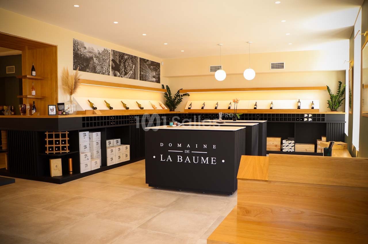 Intérieur d'une cave à vin moderne avec comptoir central, étagères de bouteilles et éclairage chaleureux.