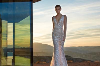 Miniature Via Novias #11 Femme portant une robe de mariée blanche avec un dos ouvert, posant dans un jardin fleuri.