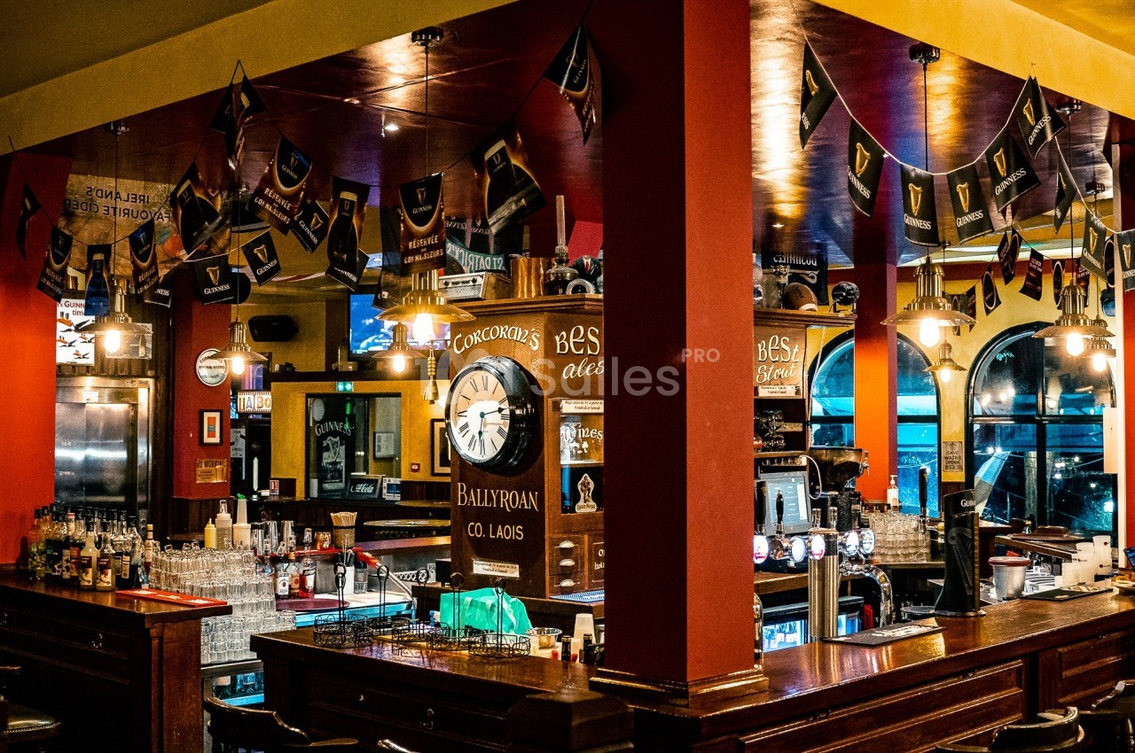Intérieur d'un pub avec un comptoir en bois, des décorations irlandaises et des lumières chaleureuses.