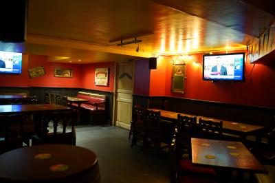 Miniature Location salle Paris 1 (Paris) - Mc Brides #9 Intérieur d'un pub avec des tables en bois, des tabourets, un tableau noir et une ambiance tamisée.