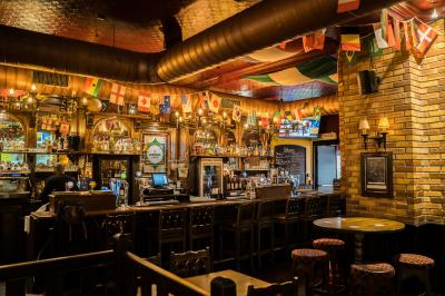 Miniature Location salle Paris 1 (Paris) - Mc Brides #17 Intérieur d'un pub avec des tables en bois, des tabourets, un tableau noir et une ambiance tamisée.