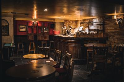 Miniature Location salle Paris 1 (Paris) - Mc Brides #23 Intérieur d'un pub avec des tables en bois, des tabourets, un tableau noir et une ambiance tamisée.