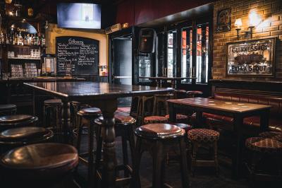Miniature Location salle Paris 1 (Paris) - Mc Brides #27 Intérieur d'un pub avec des tables en bois, des tabourets, un tableau noir et une ambiance tamisée.