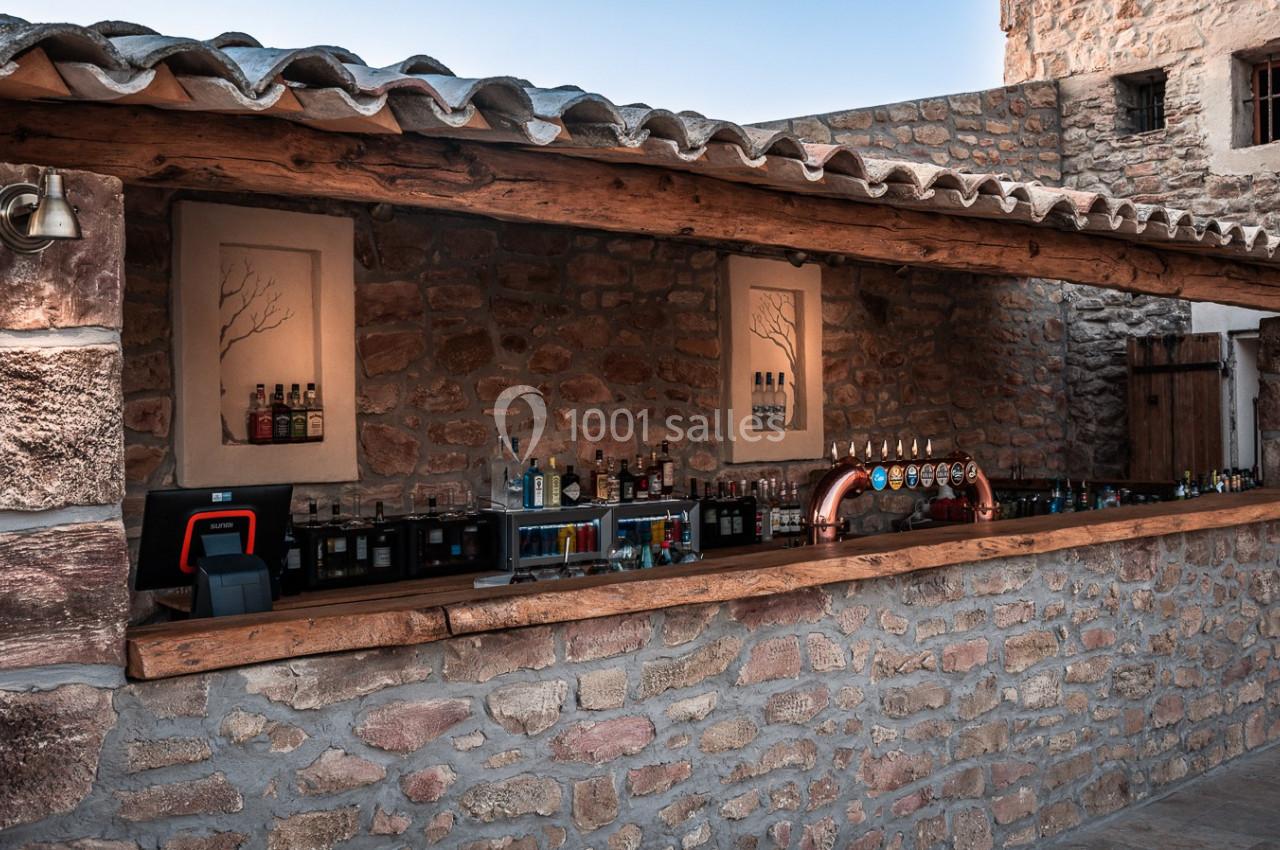 Location salle Aix-en-Provence (Bouches-du-Rhône) - Maneo #9 Bar extérieur en pierre avec comptoir en bois, équipé de tireuses à bière et de bouteilles alignées sur des étagères.