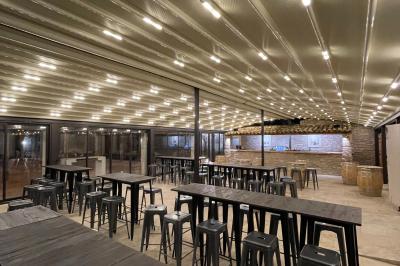 Miniature Location salle Aix-en-Provence (Bouches-du-Rhône) - Maneo #5 Salle rustique avec murs en pierre, tonneaux en bois servant de tables, tabourets métalliques et éclairage chaleureux.