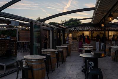 Miniature Location salle Aix-en-Provence (Bouches-du-Rhône) - Maneo #7 Salle rustique avec murs en pierre, tonneaux en bois servant de tables, tabourets métalliques et éclairage chaleureux.