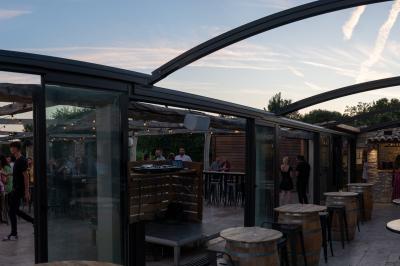 Miniature Location salle Aix-en-Provence (Bouches-du-Rhône) - Maneo #8 Salle rustique avec murs en pierre, tonneaux en bois servant de tables, tabourets métalliques et éclairage chaleureux.