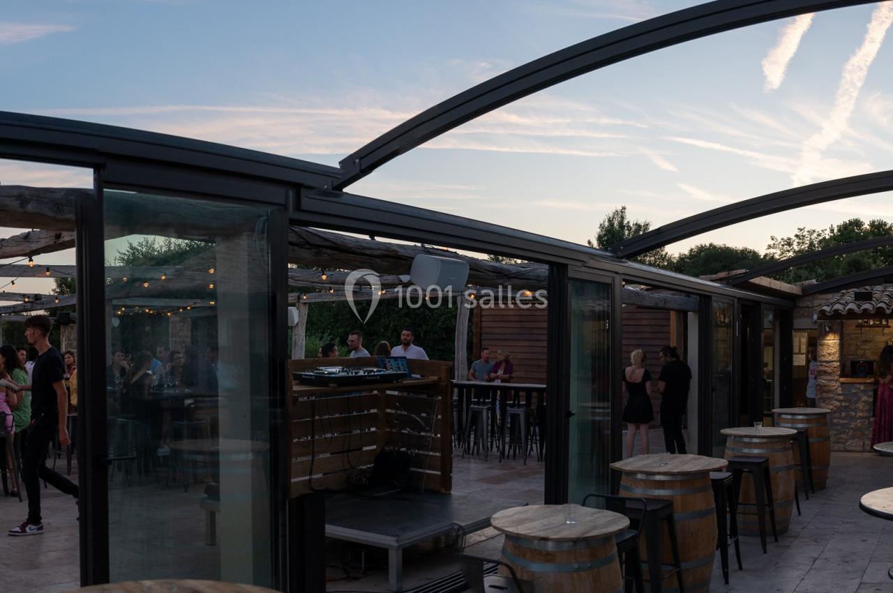 Location salle Aix-en-Provence (Bouches-du-Rhône) - Maneo #8 Terrasse couverte avec des tables et des chaises, des invités debout et assis, au coucher du soleil.