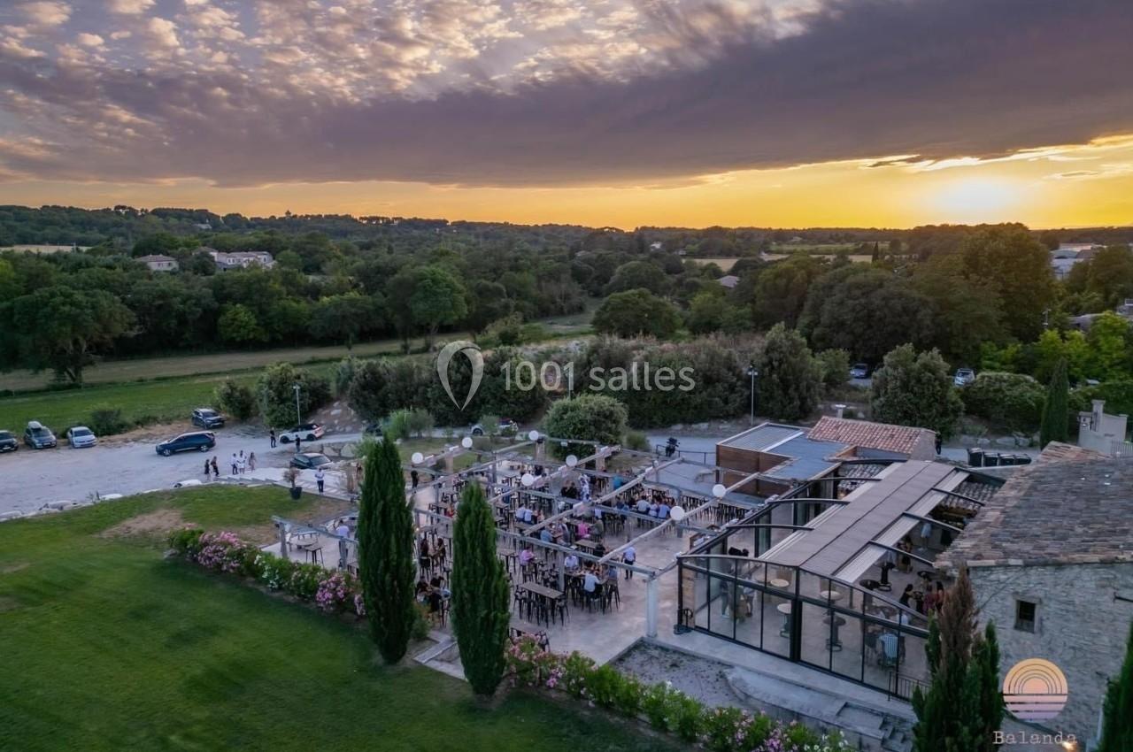 Location salle Aix-en-Provence (Bouches-du-Rhône) - Maneo #16 Vue aérienne d'une terrasse animée entourée de verdure au coucher du soleil, avec un ciel partiellement nuageux.