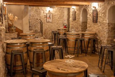 Miniature Location salle Aix-en-Provence (Bouches-du-Rhône) - Maneo #19 Salle rustique avec murs en pierre, tonneaux en bois servant de tables, tabourets métalliques et éclairage chaleureux.