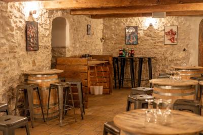 Miniature Location salle Aix-en-Provence (Bouches-du-Rhône) - Maneo #20 Salle rustique avec murs en pierre, tonneaux en bois servant de tables, tabourets métalliques et éclairage chaleureux.