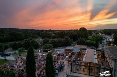 Miniature Location salle Aix-en-Provence (Bouches-du-Rhône) - Maneo #1 Salle rustique avec murs en pierre, tonneaux en bois servant de tables, tabourets métalliques et éclairage chaleureux.