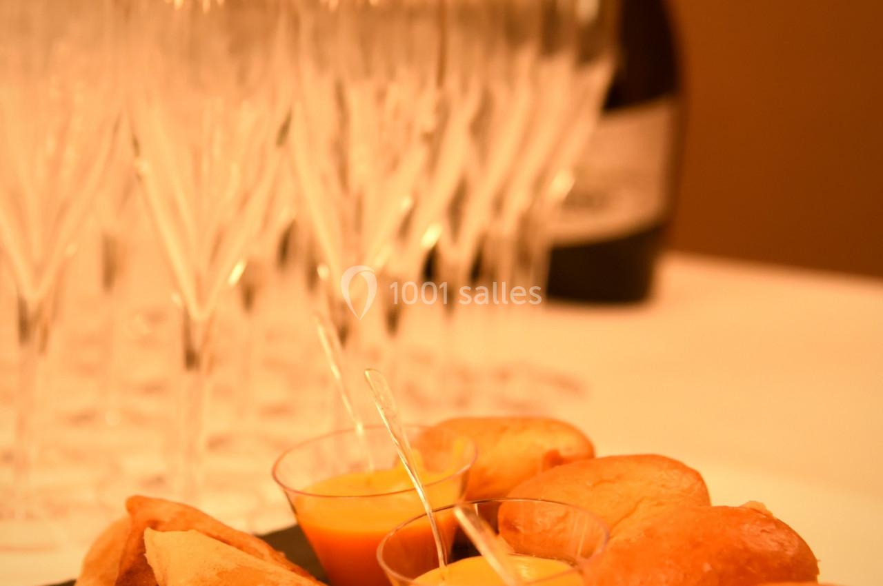 Plateau de bouchées salées avec verrines de soupe, samoussas et petits pains, accompagné de flûtes et bouteilles de…