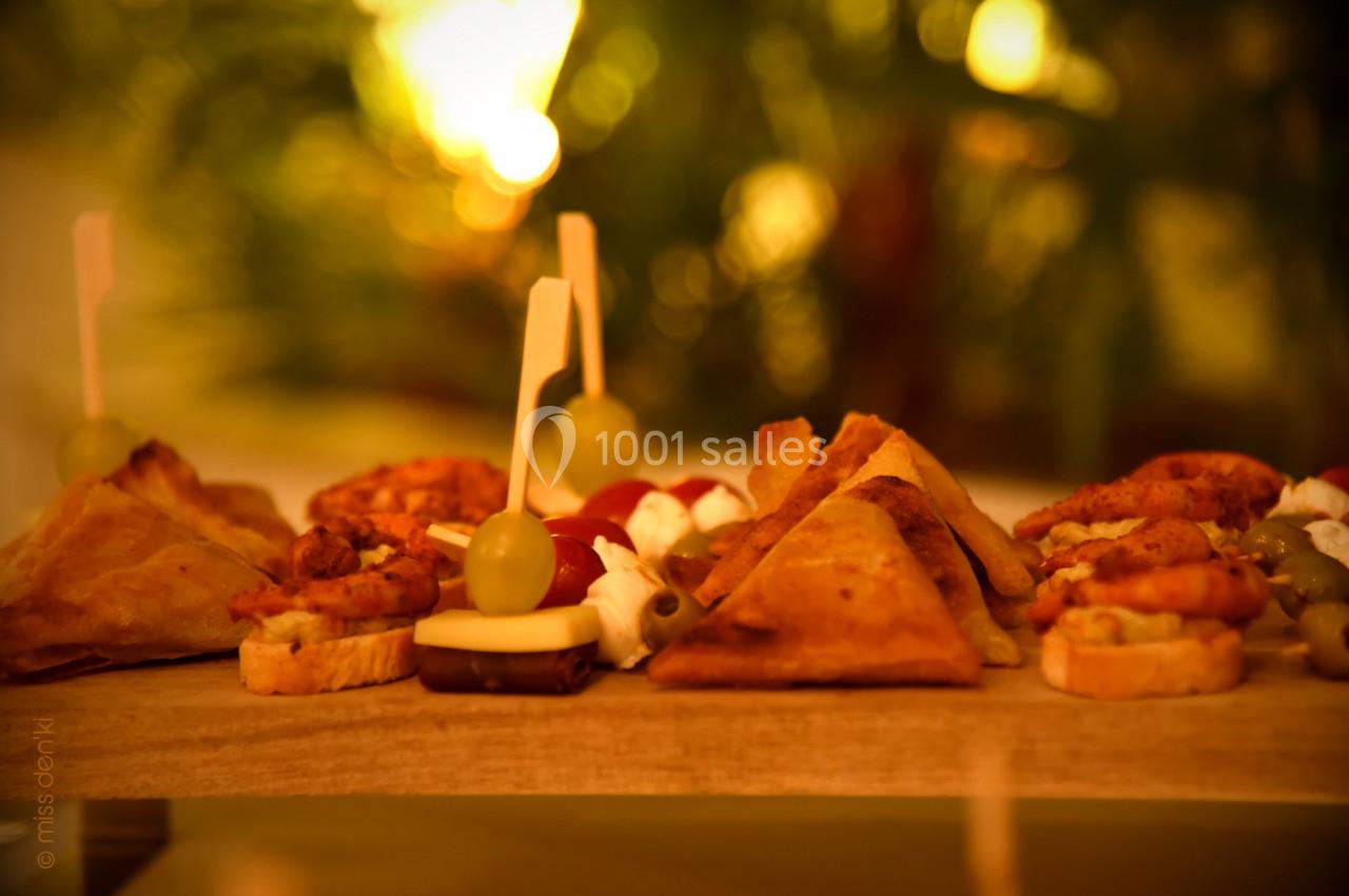 Plateau de bouchées apéritives variées, incluant samoussas, brochettes et amuse-bouches, sur une table en bois.