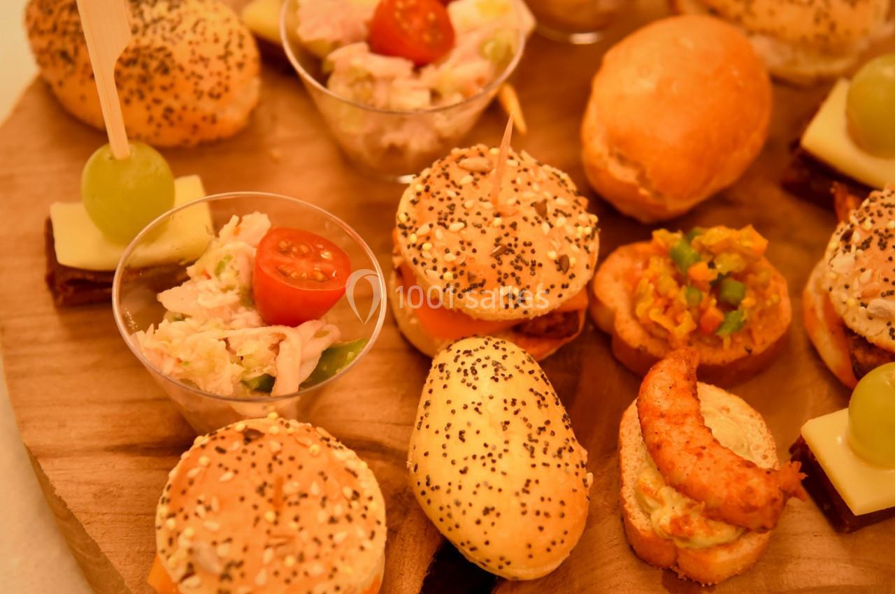 Plateau en bois garni de mini-sandwichs, verrines, bouchées salées et brochettes apéritives avec raisin et fromage.