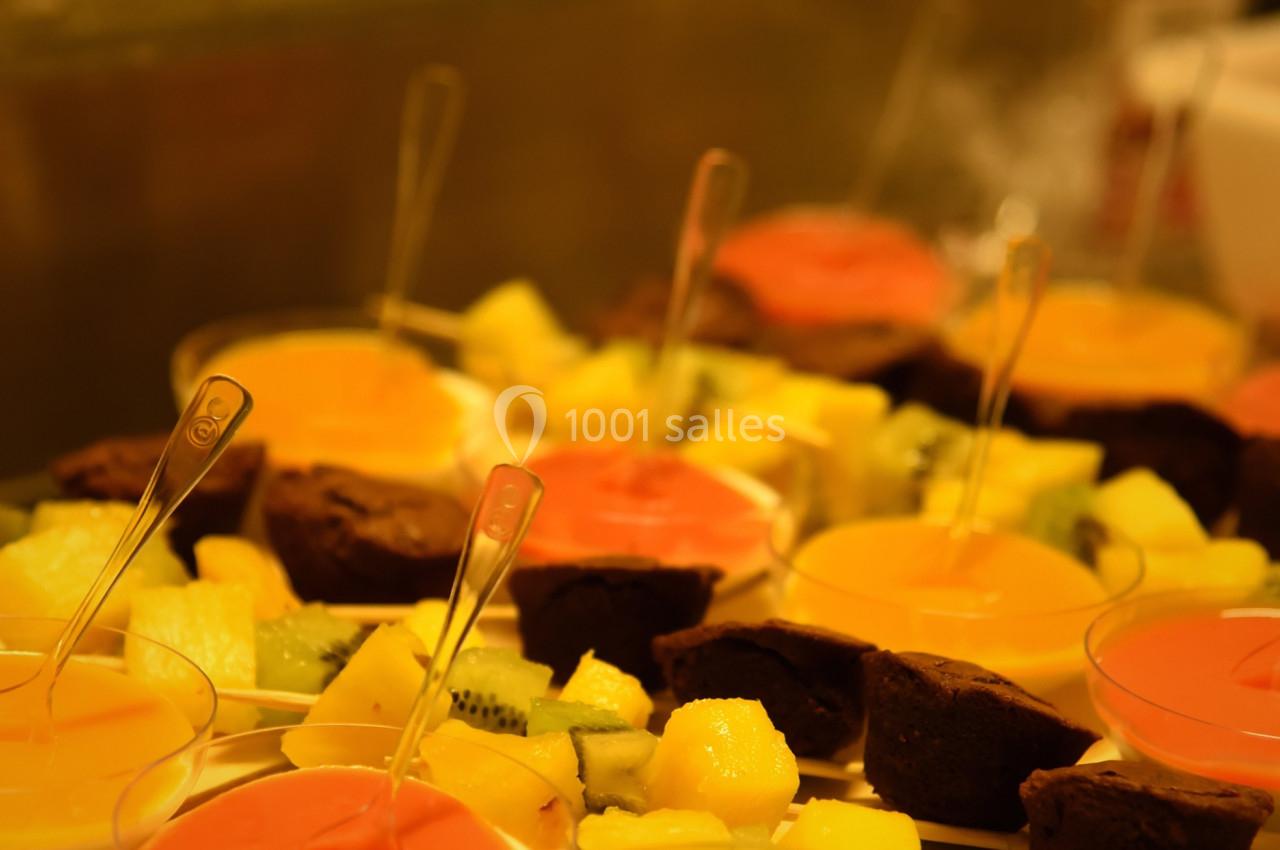 Assortiment de desserts colorés comprenant des verrines de fruits et des parts de gâteau disposés sur un plateau.