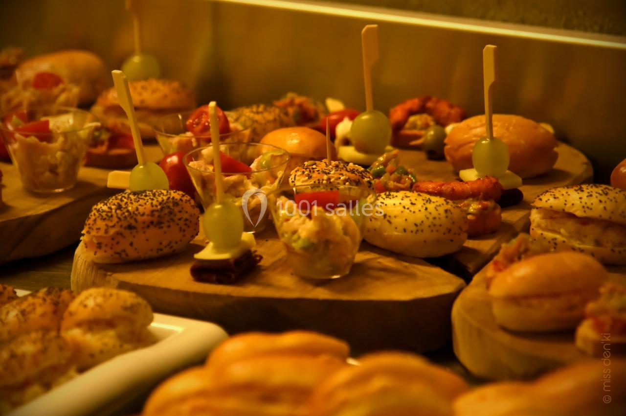 Plateau de mini-burgers, verrines et amuse-bouches variés disposés sur des planches en bois.