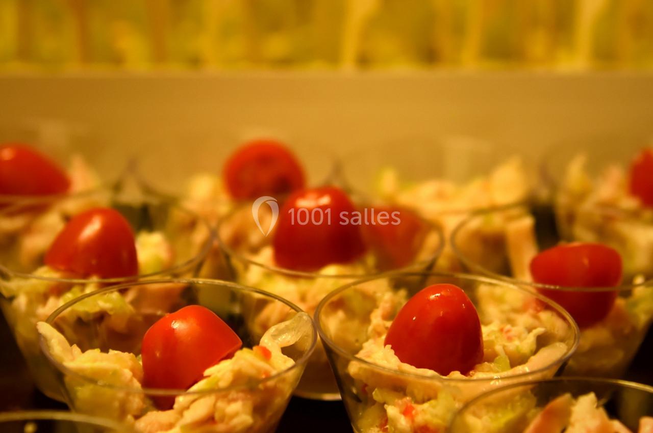 Verrines garnies de salade, crevettes et tomates cerises, disposées sur une table dans un cadre chaleureux.