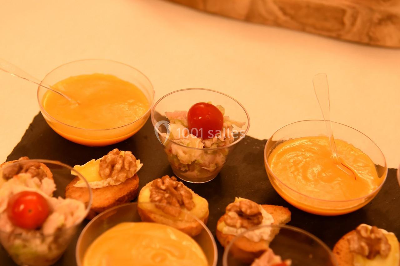 Assortiment de verrines et amuse-bouches variés disposés sur une ardoise et une planche en bois.