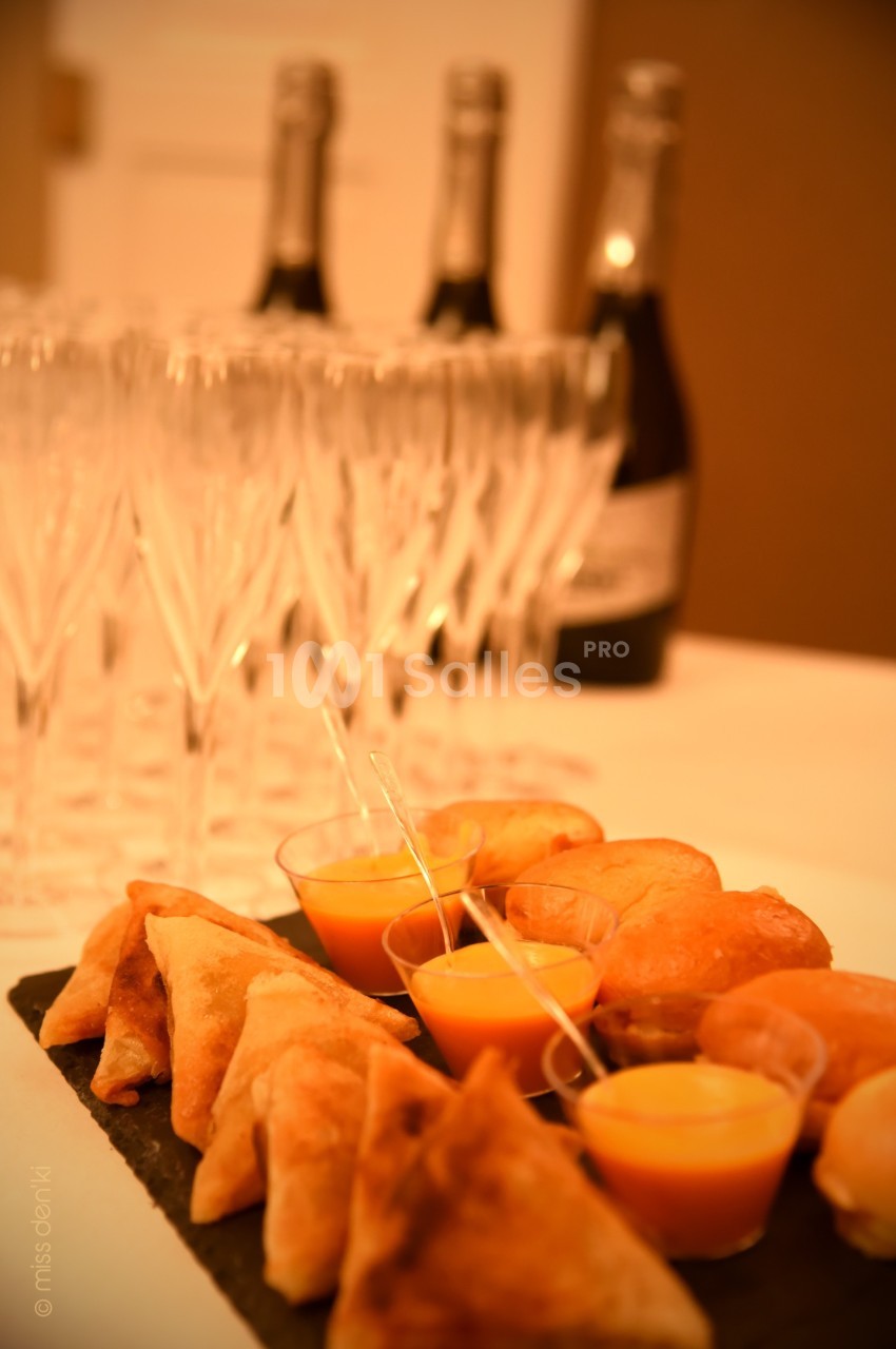 Plateau de bouchées apéritives avec samoussas, verrines et petits pains, accompagné de flûtes et bouteilles de champagne.
