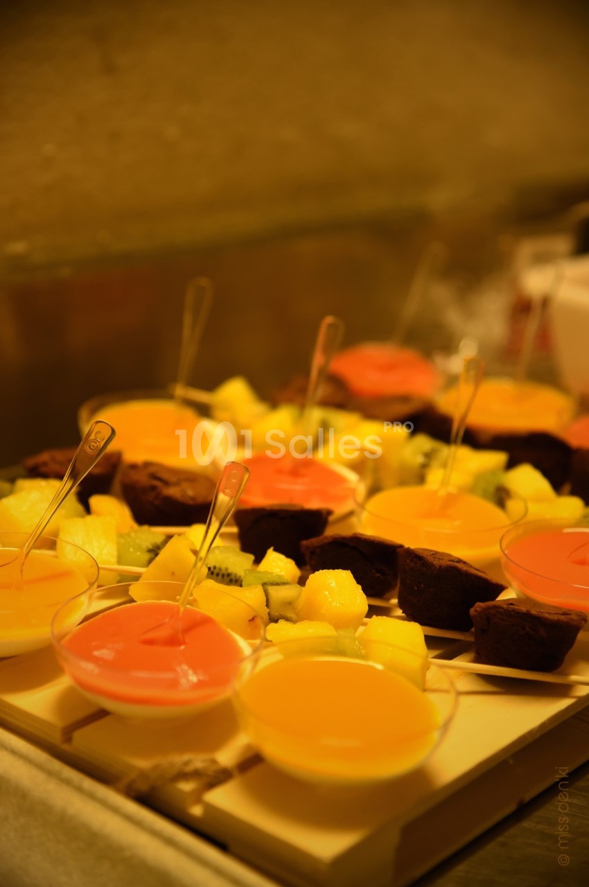 Desserts variés présentés sur un plateau, comprenant des verrines colorées, des fruits et des morceaux de gâteau.