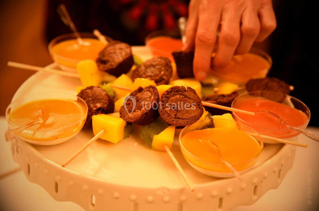 Plateau de desserts avec brochettes de fruits, mini-gâteaux au chocolat et verrines de sauces colorées.