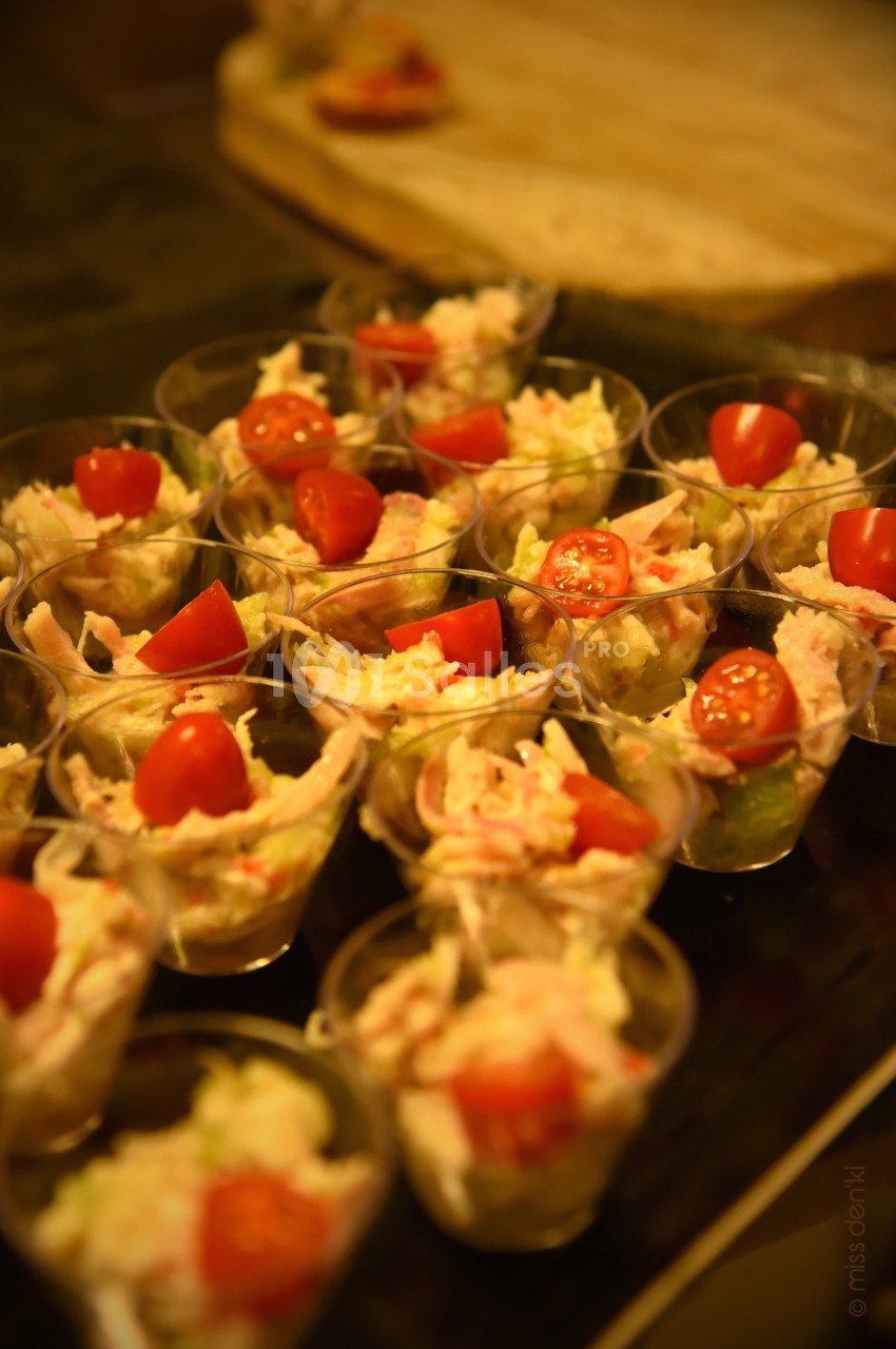 Verrines garnies de salade composée, morceaux de crabe et tomates cerises, présentées sur un plateau.