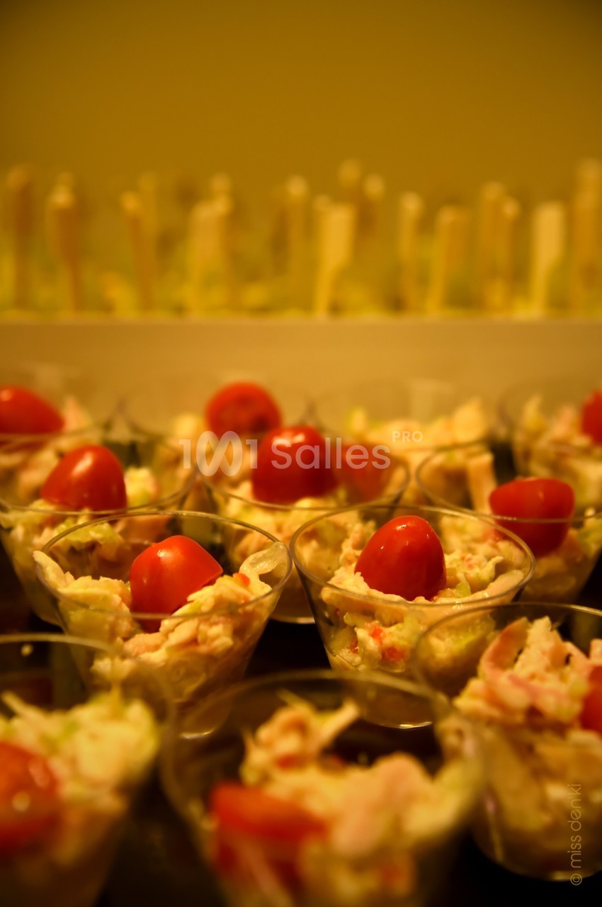 Verrines garnies de salade, crevettes et tomates cerises, disposées sur une table dans un cadre chaleureux.