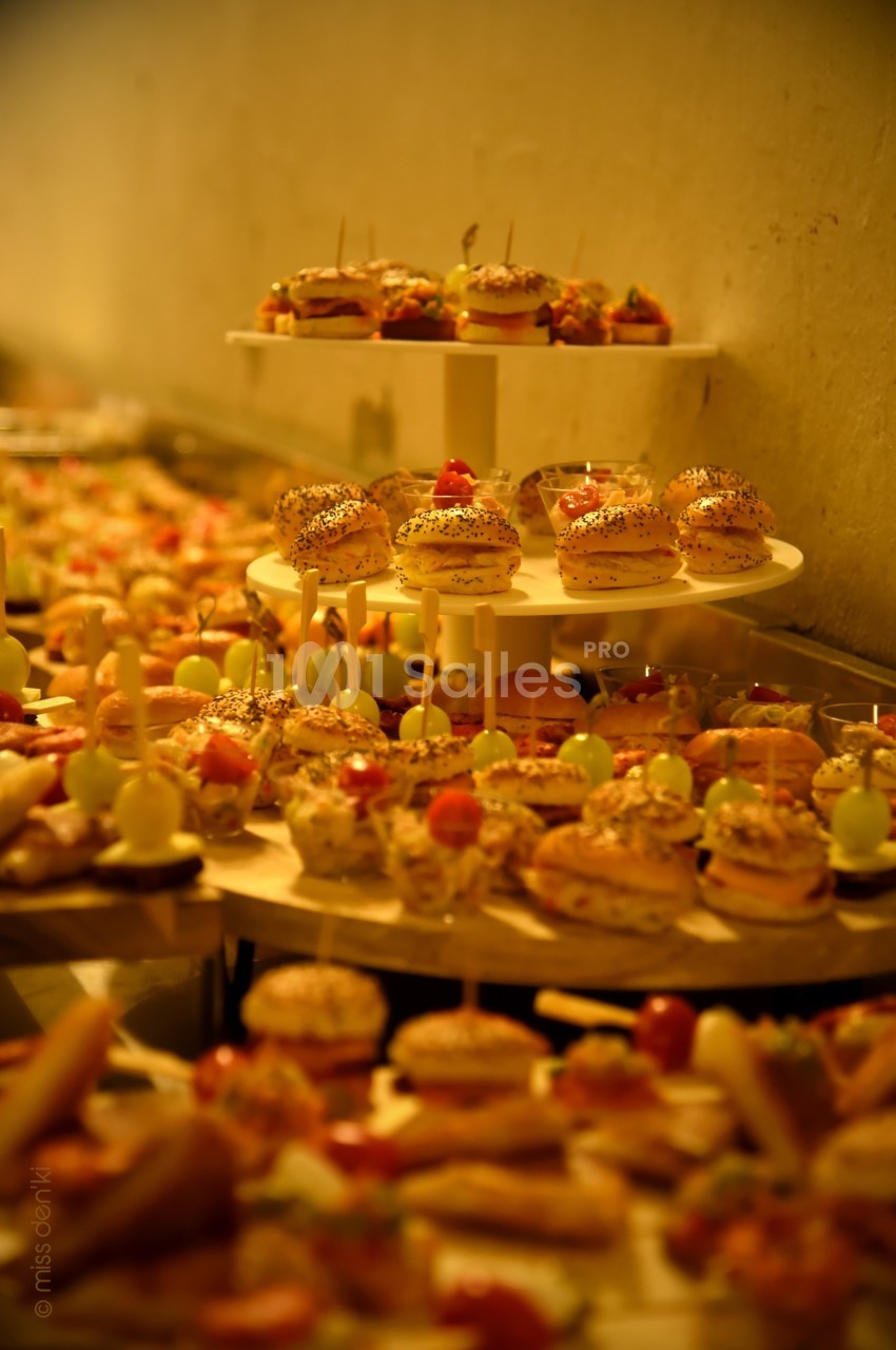 Buffet garni de petits sandwichs, brochettes et amuse-bouches disposés sur des plateaux en bois et étagères.