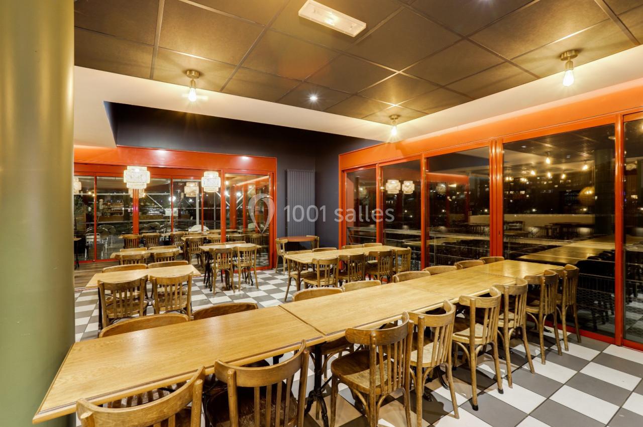 Salle de restaurant vide avec des tables en bois alignées, chaises assorties et grandes baies vitrées donnant sur l…