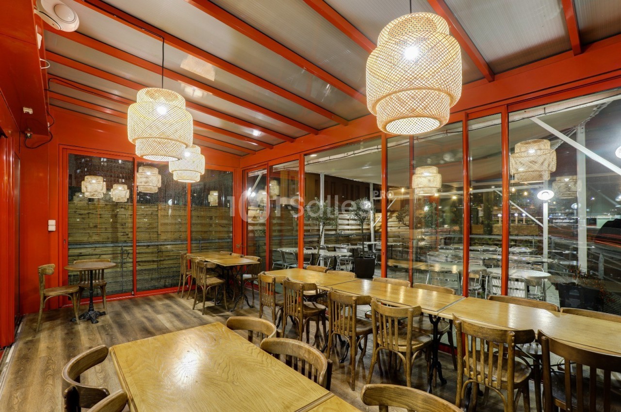Salle de restaurant lumineuse avec des tables en bois, des chaises assorties et des suspensions en osier.