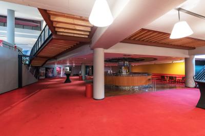 Façade éclairée d'un cinéma moderne en soirée, avec quelques passants devant l'entrée.