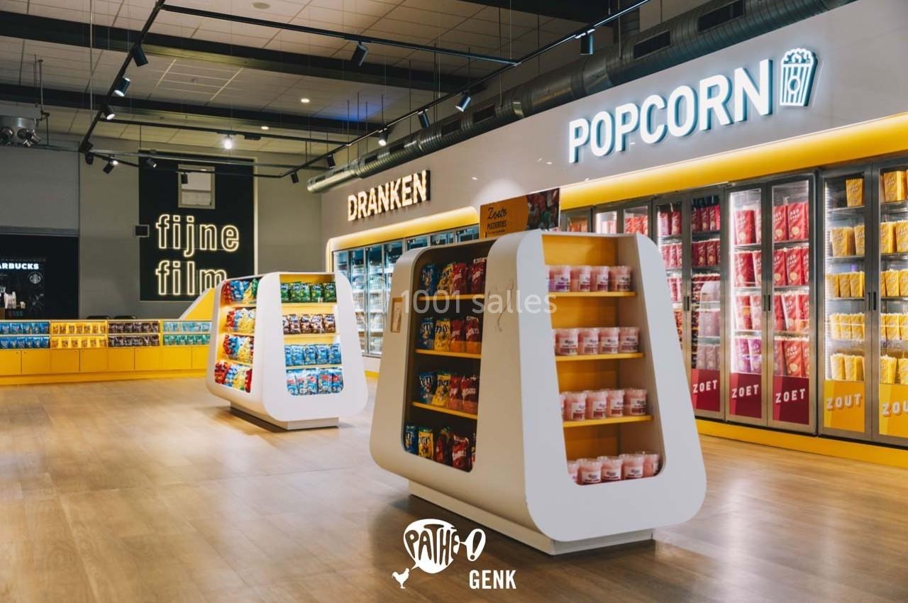 Rayons d'un magasin proposant des snacks, bonbons et popcorn, avec un éclairage moderne et des étagères colorées.