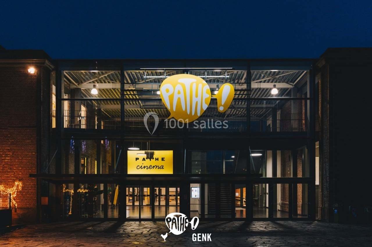 Façade vitrée d'un cinéma Pathé illuminé de nuit, avec le logo jaune visible au-dessus de l'entrée principale.