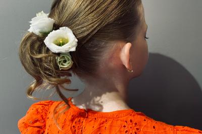 Miniature Hair by elle  #2 Femme de dos avec des cheveux blonds coiffés en tresse et chignon, portant un pull beige près d'une fenêtre.