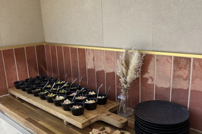 Grand arbre au centre d'un jardin verdoyant, avec une maison en pierre et une allée gravillonnée en arrière-plan.