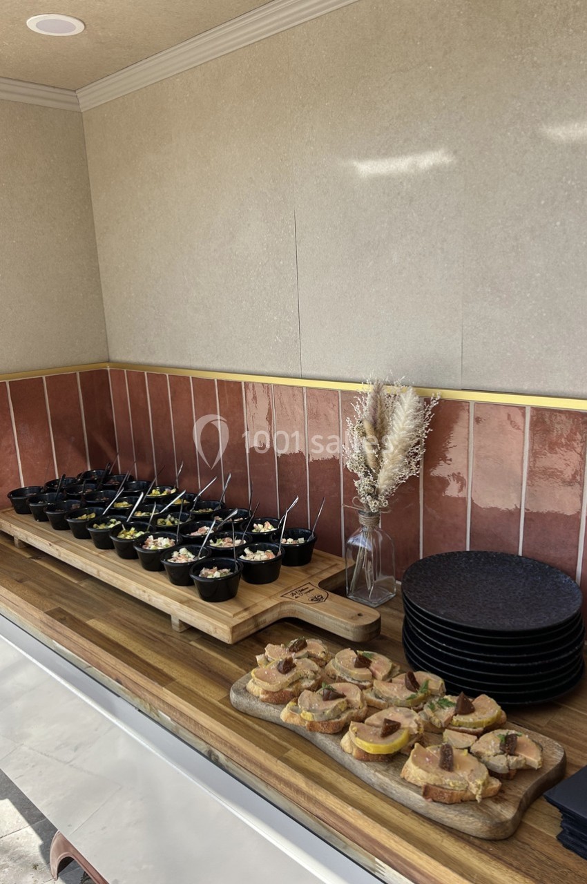 Buffet avec verrines et toasts disposés sur des planches en bois, près d'assiettes empilées et d'une décoration florale.