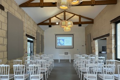 Grand arbre au centre d'un jardin verdoyant, avec une maison en pierre et une allée gravillonnée en arrière-plan.